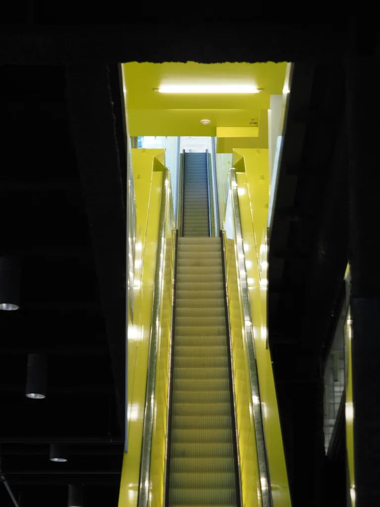 a tall yellow multi-story escalator