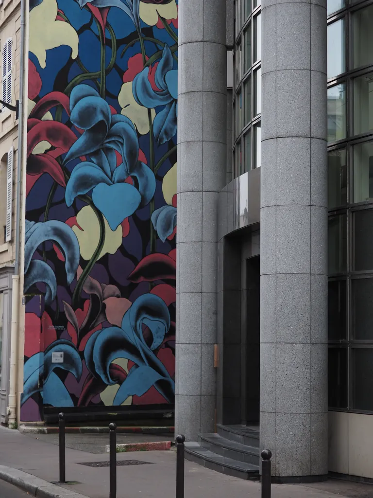 a floral mural beside stone pillars and a curved glass wall