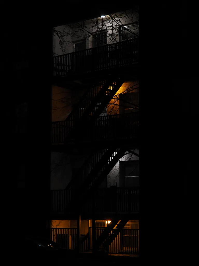 a four floor apartment building with alternating white and yellow light