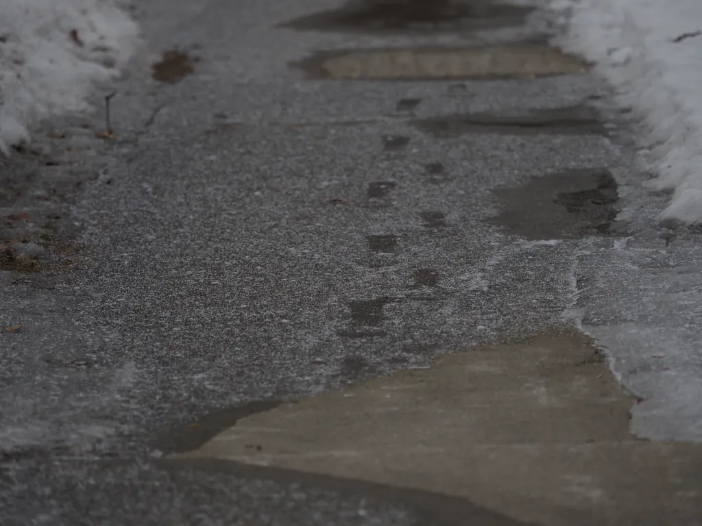 footprints on ice covered in a loose powdering of snow