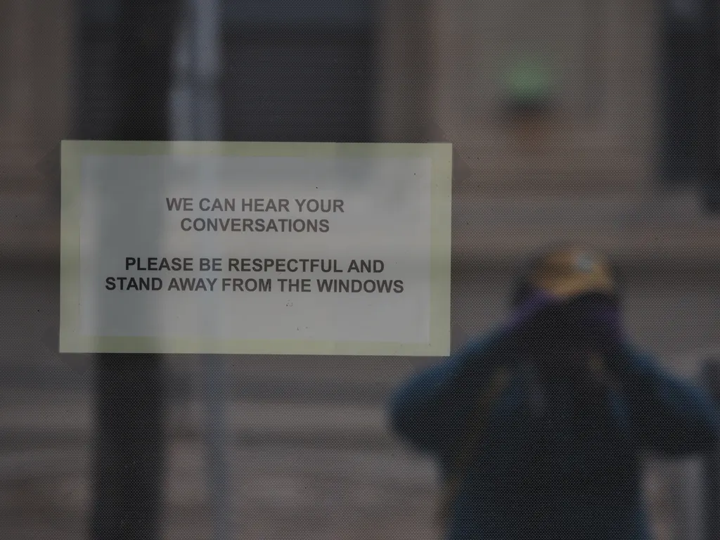 a selfie taken by a sign: we can hear your conversations. please be respectful and stand away from the windows