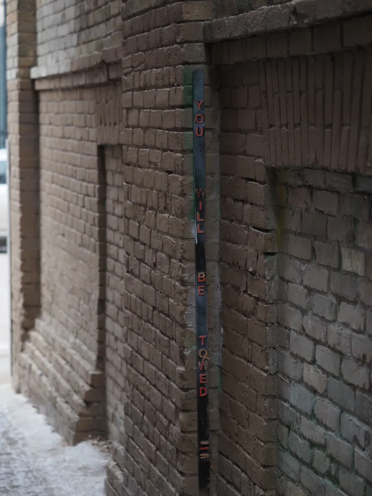 a vertical sign in a brick tunnel: you will be towed