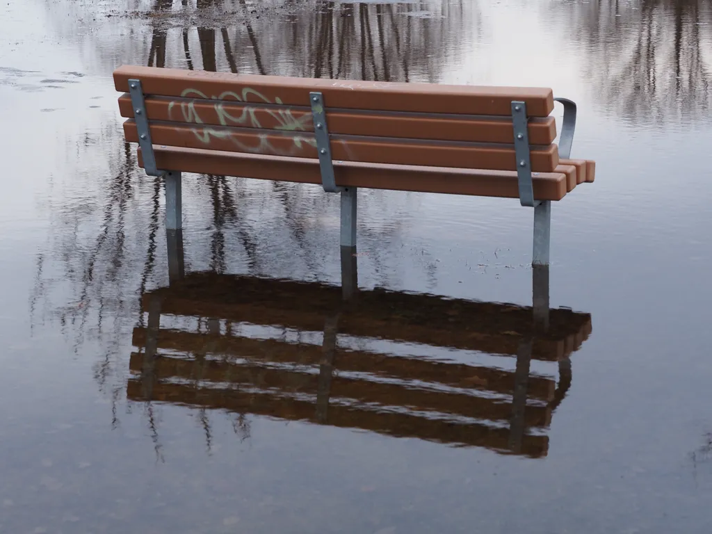 a bench reflect in a puddle