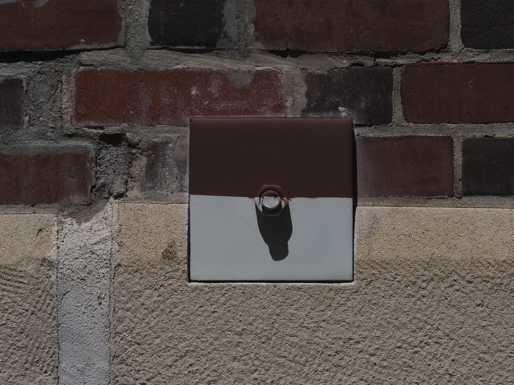 a metal plate on a building painted to match the brick and concrete around it