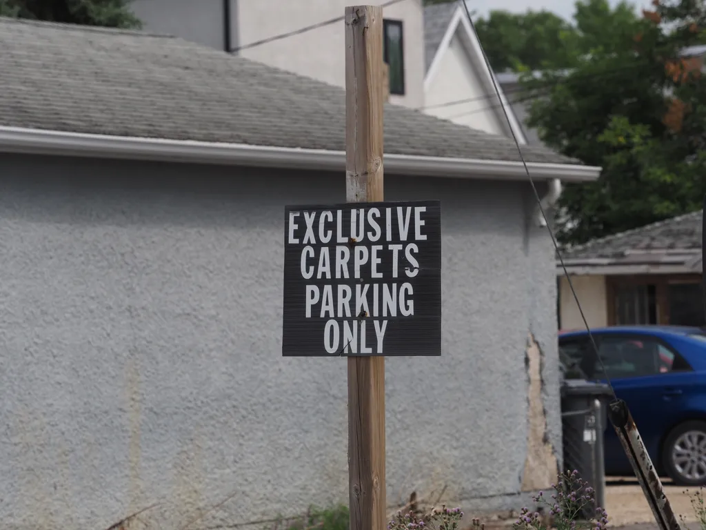 a sign: Exclusive Carpets Parking Only