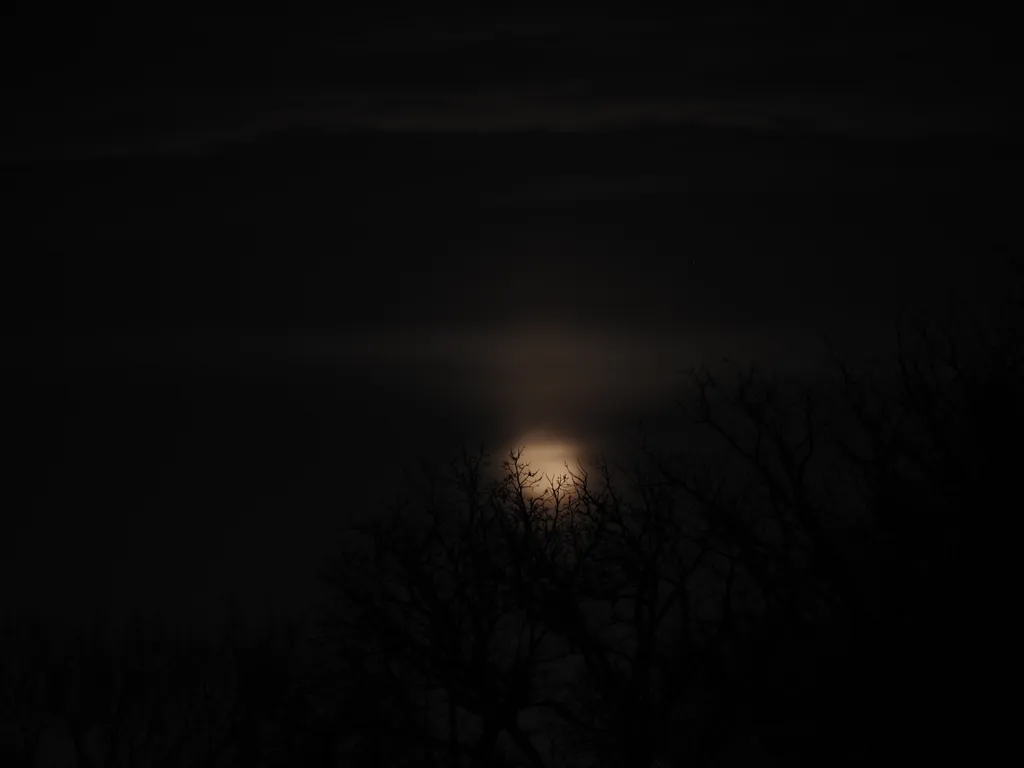 a shining moon behind clouds