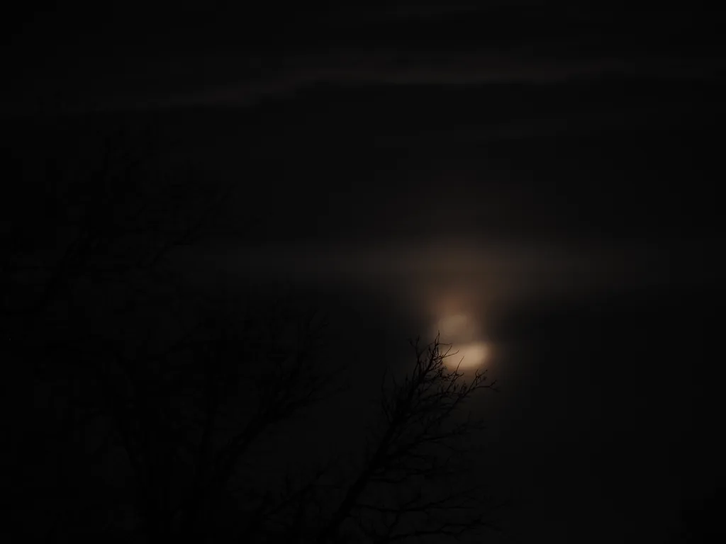 a shining moon behind clouds
