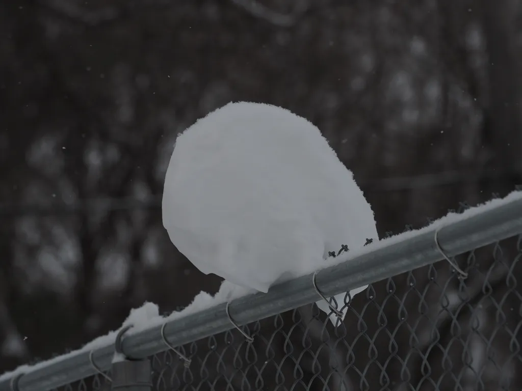 a block of snow on top of a a chain-link fence