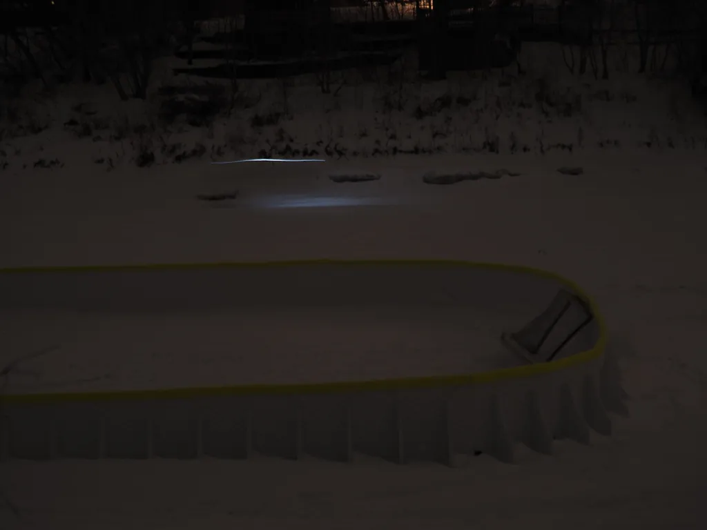 a biker going by a portable rink on a river at night
