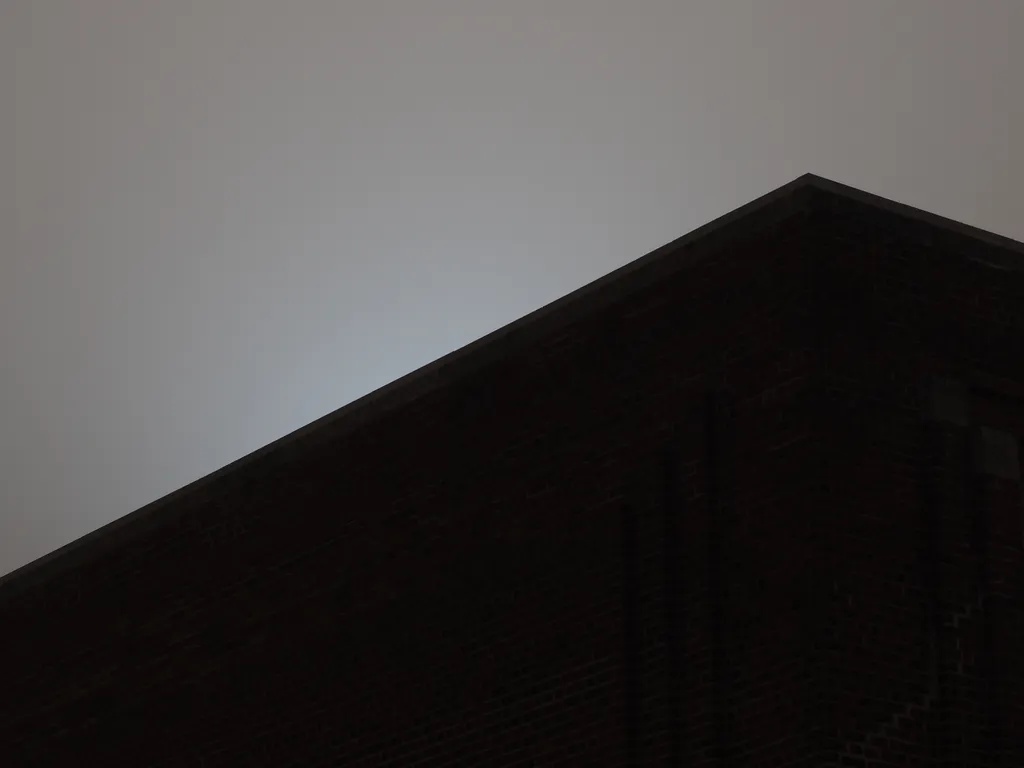 the sun behind a brick building