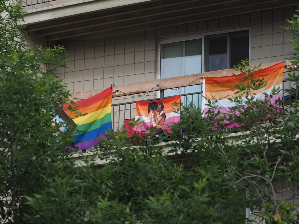 3 pride flags, one of which featuring two women kissing